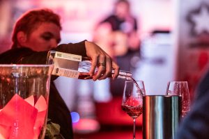 Event im FC St. Pauli-Museum am Millerntor. Eine Person schenkt Wein aus einer Flasche in zwei Gläser.